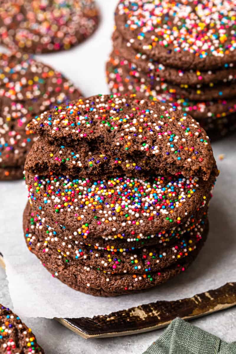 stack of chocolate butter cookies on a white plate with the top cookie broken in half