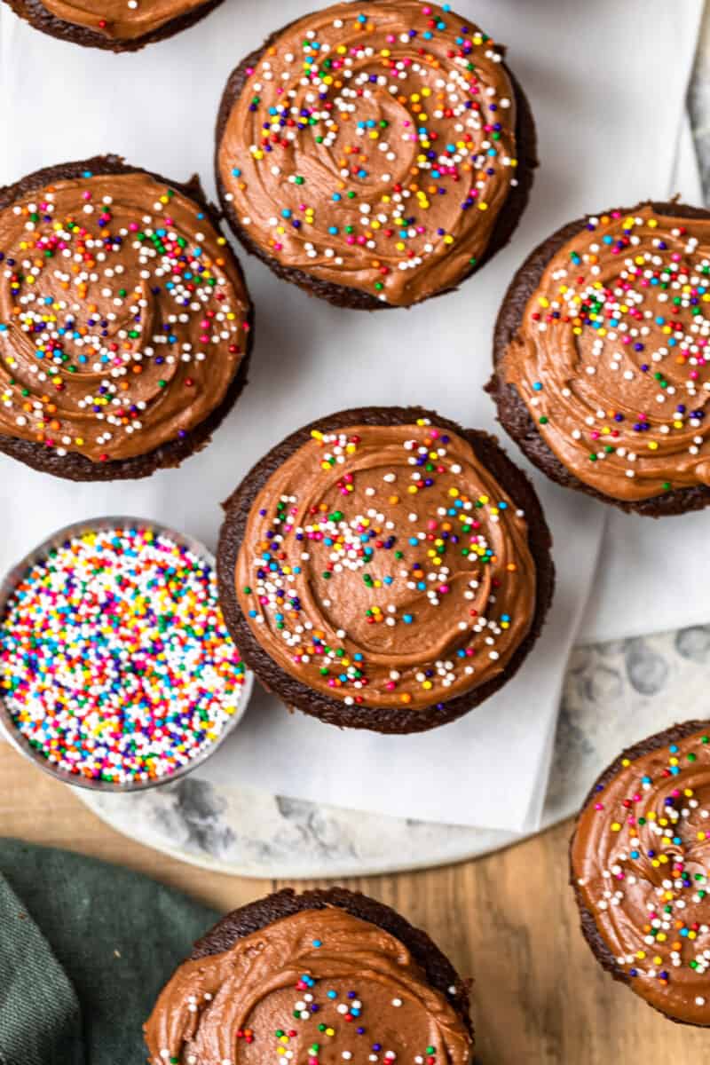 overhead image of chocolate cupcakes topped with chocolate frosting and sprinkles