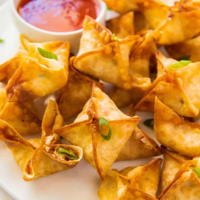 crab rangoon on white platter with sweet and sour sauce