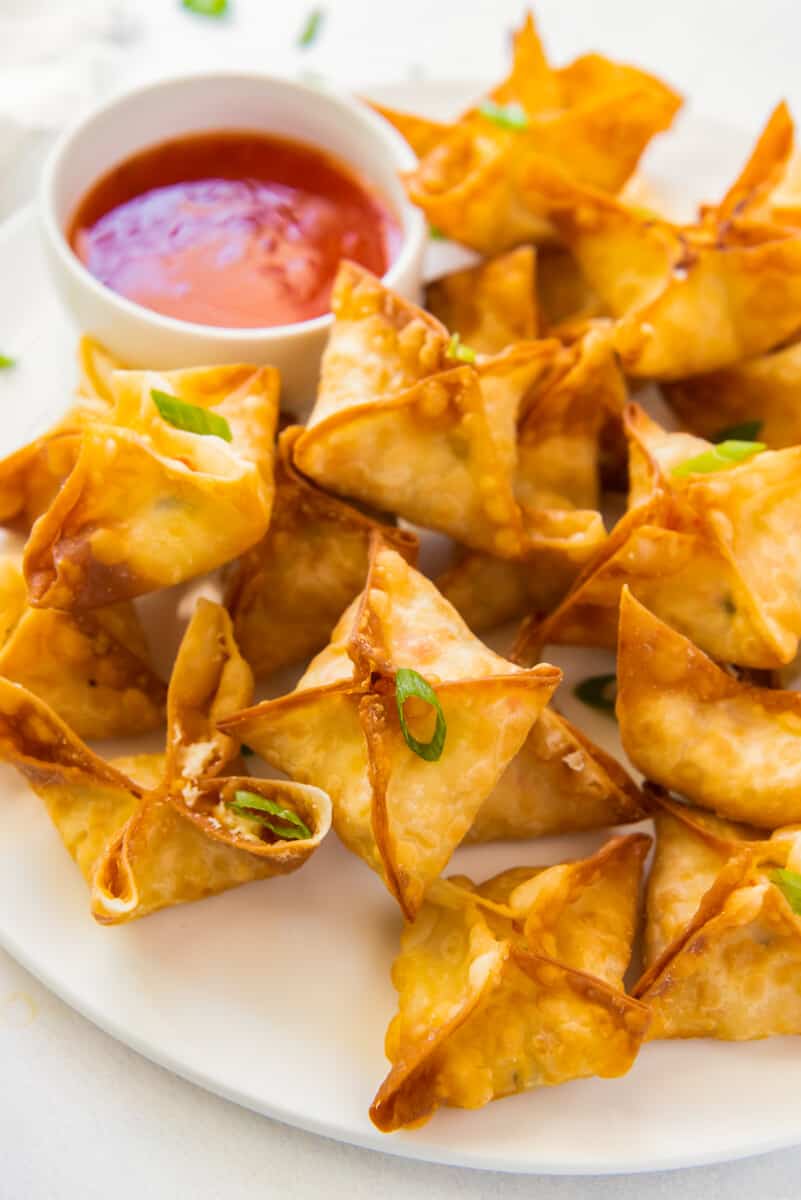 crab rangoon on white platter with sweet and sour sauce