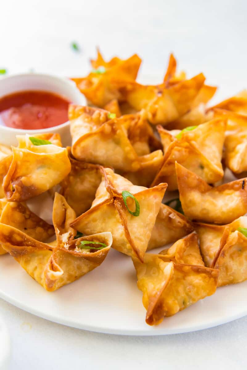 crab rangoon on white platter with sweet and sour sauce