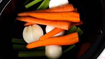 carrots, celery, and onions inside of a slow cooker