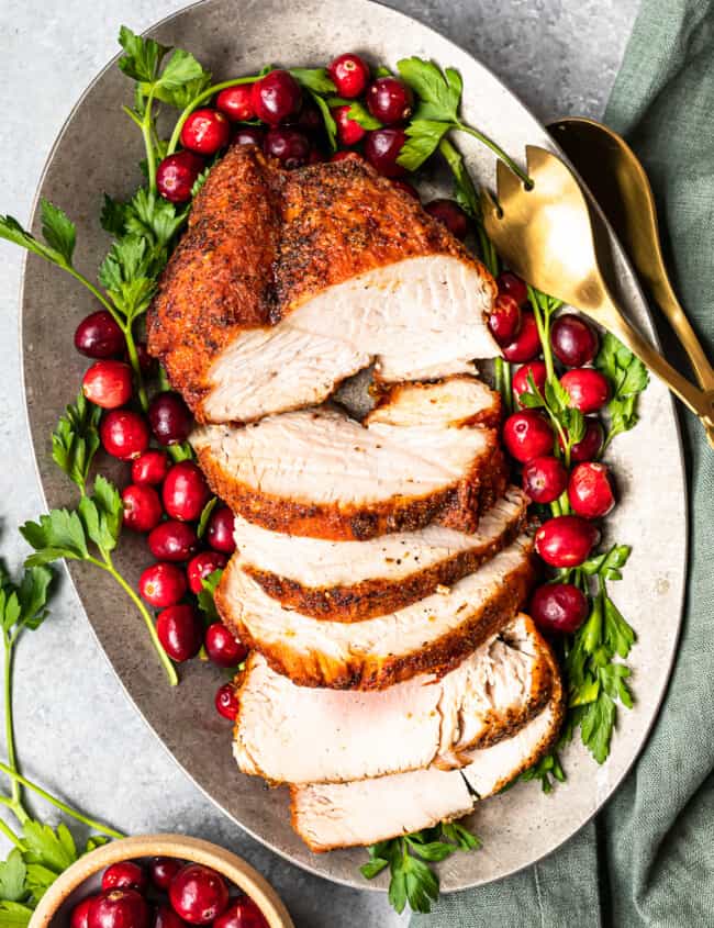 slices of deep fried turkey on a serving platter with cranberry and herb garnishes