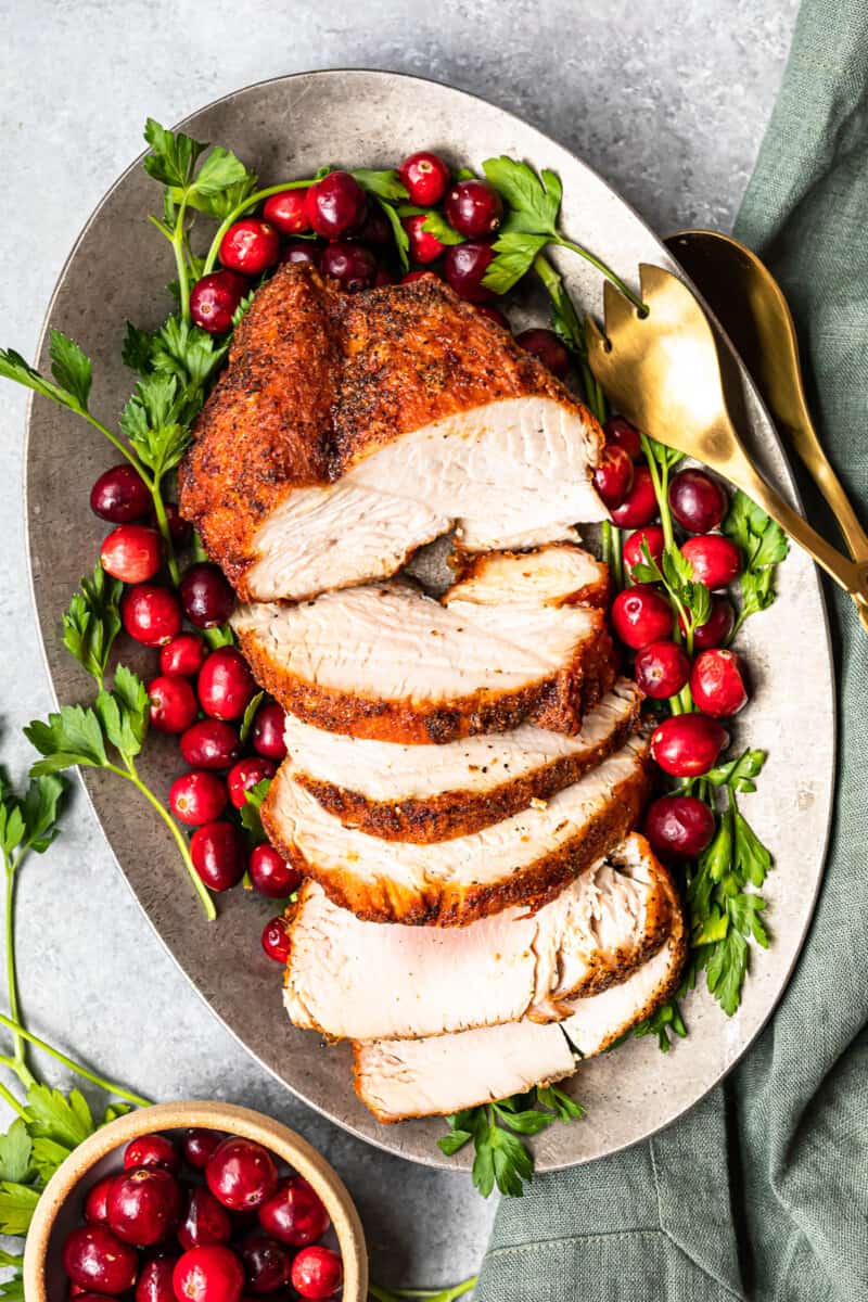 slices of deep fried turkey on a serving platter with cranberry and herb garnishes