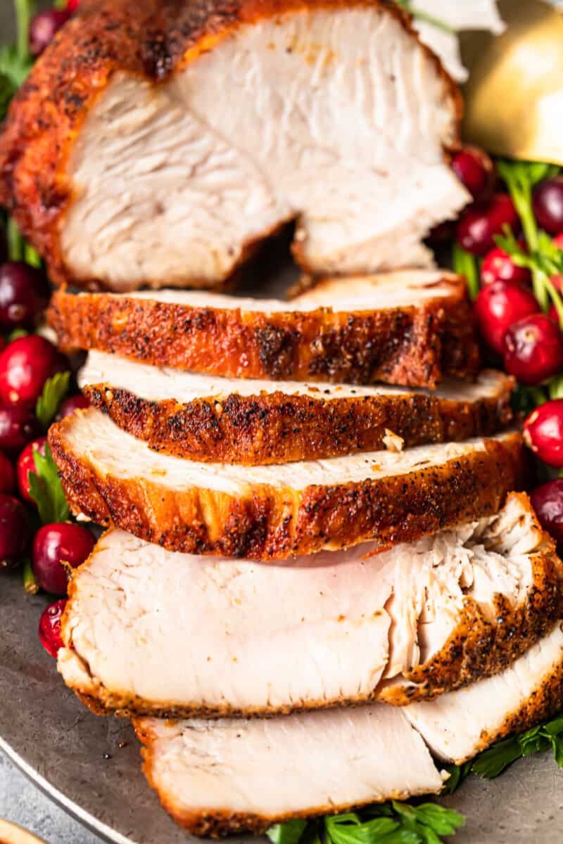 slices of deep fried turkey on a serving platter with cranberry and herb garnishes