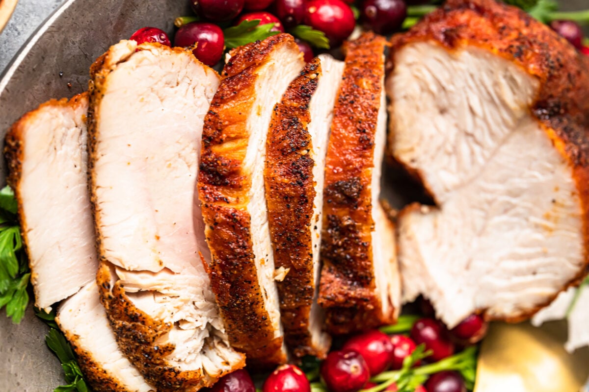 slices of deep fried turkey on a serving platter with cranberry and herb garnishes