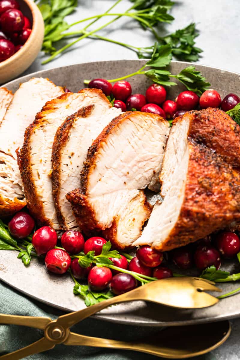 side view of slices of deep fried turkey on a serving platter with cranberry and herb garnishes