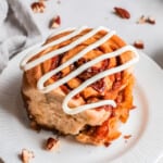 pecan caramel roll on a plate drizzled with icing