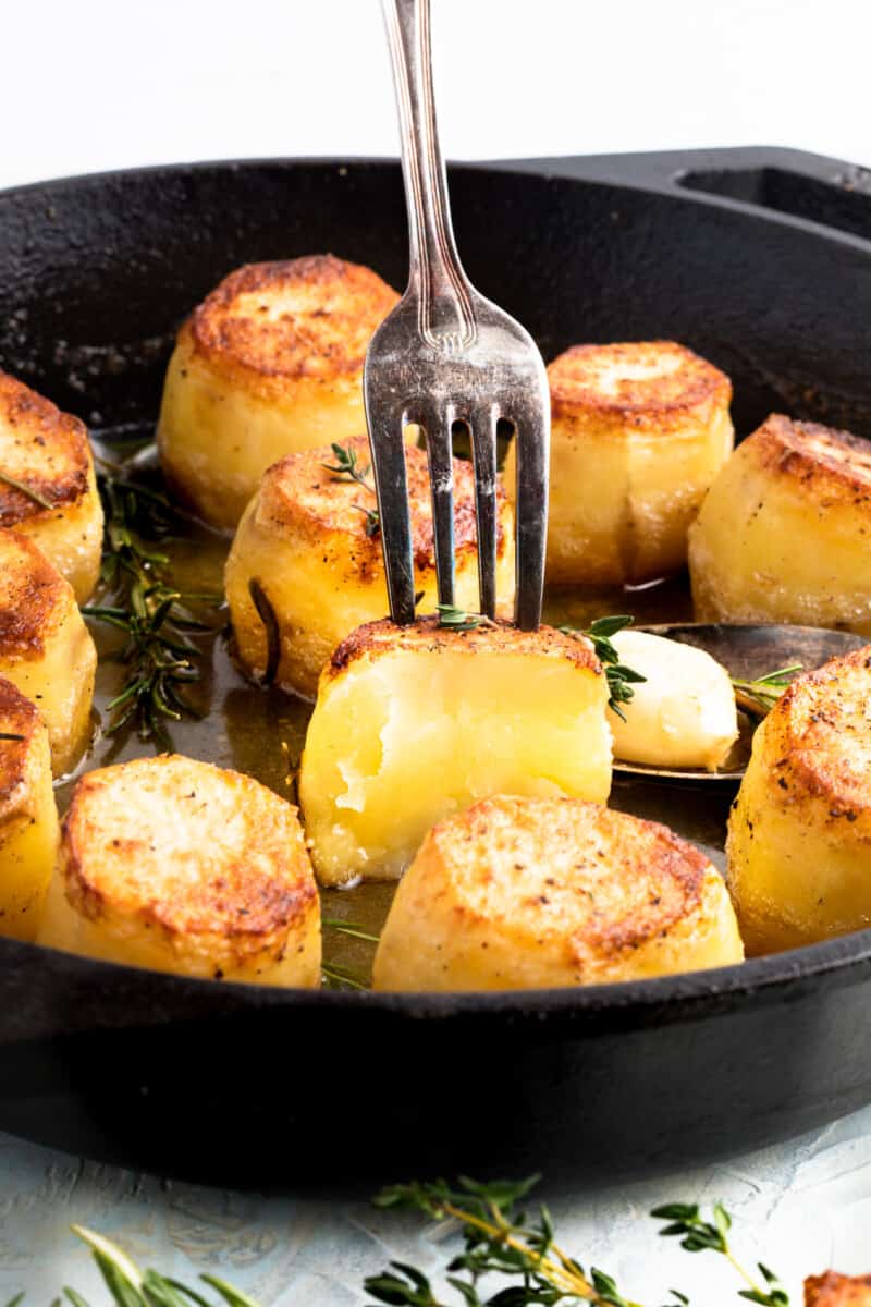 fork spearing a fondant potato in a skillet