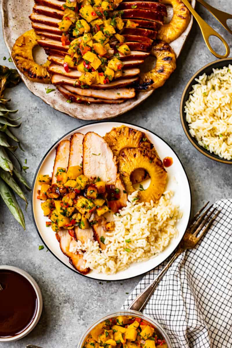 overhead image of rice, grilled pineapple slices, and slices of huli huli turkey breast topped with pineapple salsa on a white plate