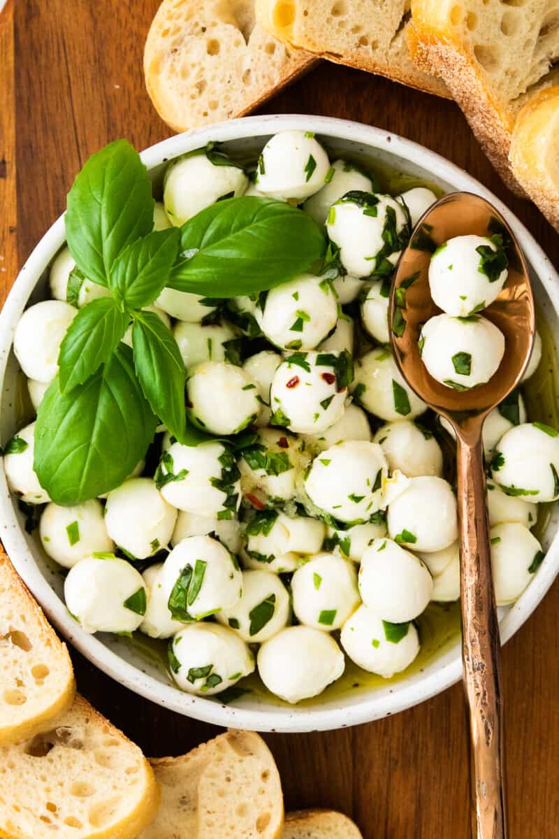 herb marinated mozzarella in white bowl with spoon