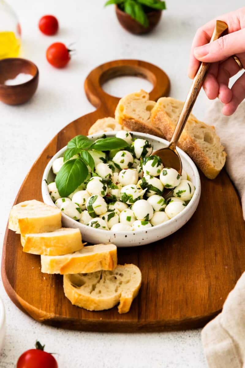 spoon dipping into herb marinated mozzarella