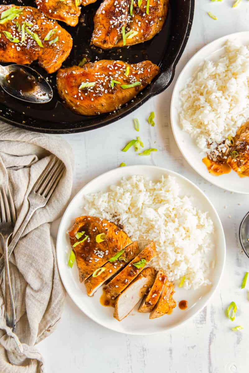 sliced honey garlic chicken breasts with rice on a white plate