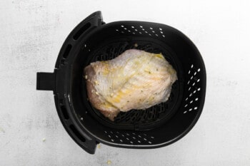 garlic rosemary turkey breast in air fryer basket before cooking