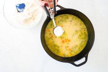 scooping dumplings into a pot of chicken and dumplings soup