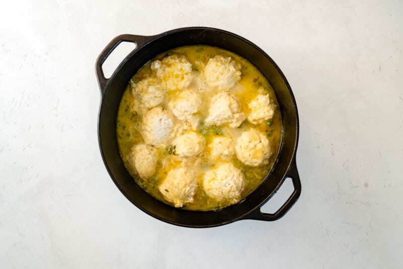 dumplings added to chicken soup in a pot