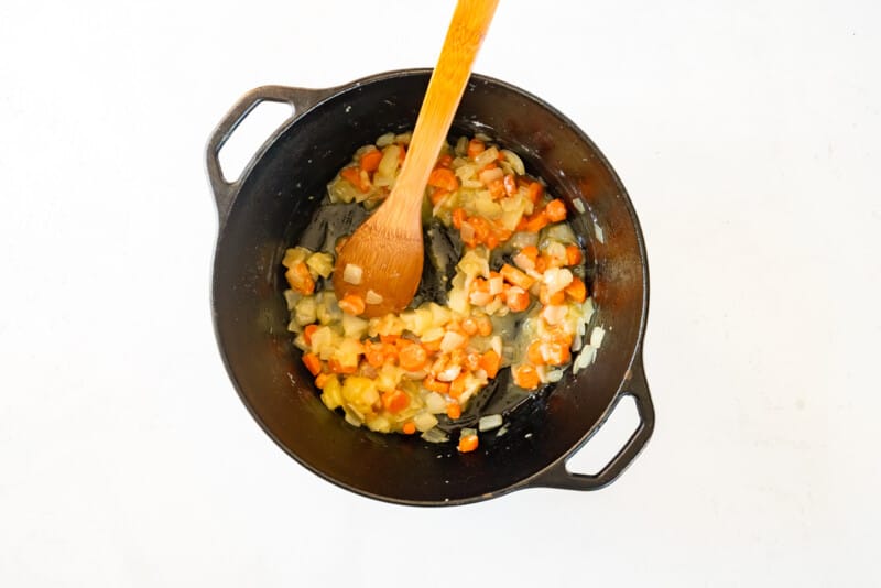 cooked veggies for chicken and dumplings in a pot with a wood spoon