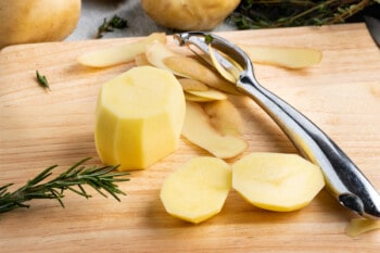 peeled Yukon gold potatoes with the ends cut off on a cutting board