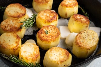 fondant potatoes in a skillet with butter and herbs