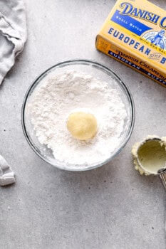 cookie dough ball in a bowl of powdered sugar