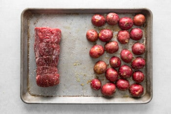 beef tenderloin and red potatoes on a sheet pan before baking
