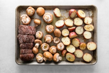 beef tenderloin with mushrooms and red potatoes on a sheet pan