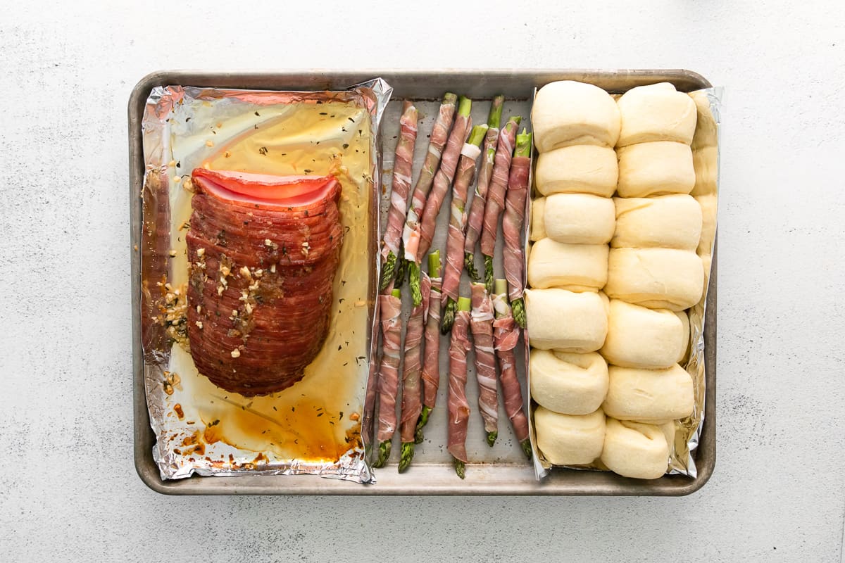 ham, prosciutto wrapped asparagus, and rolls on a sheet pan before baking