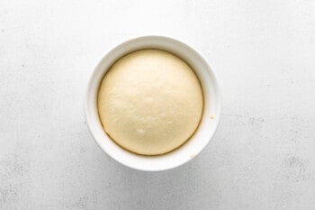 parker house dinner rolls dough in a white bowl after rising