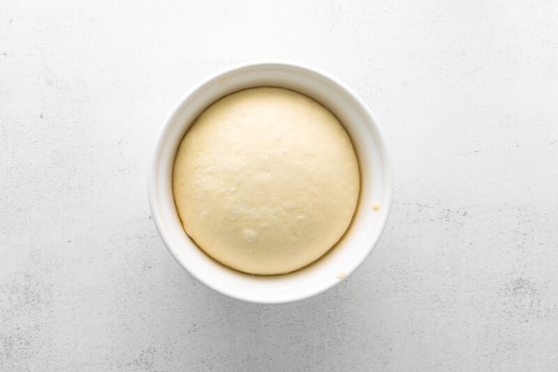 parker house dinner rolls dough in a white bowl after rising