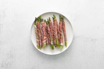 prosciutto wrapped asparagus spears on a white plate