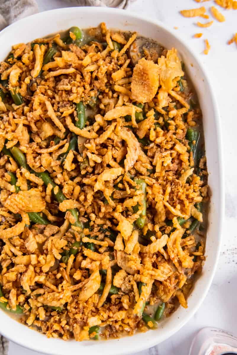 green bean casserole topped with fried onions in a white casserole dish