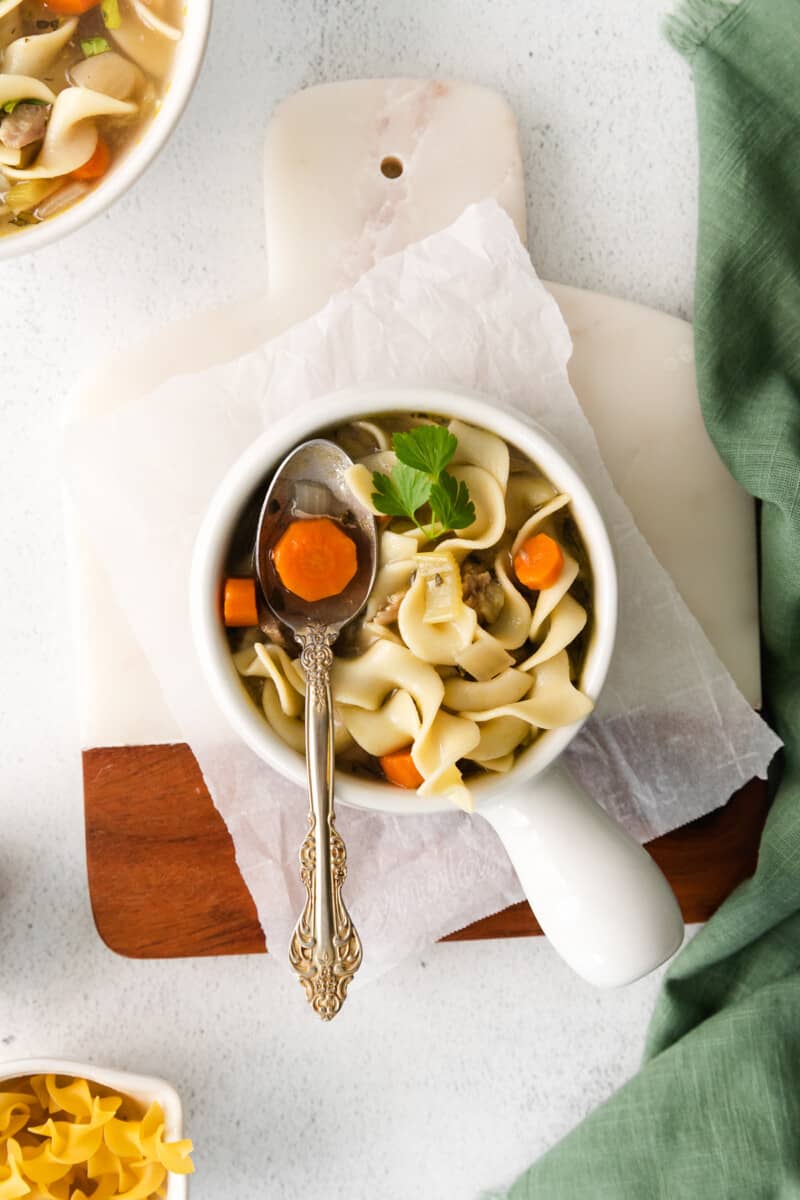 overhead image of turkey noodle soup in a white bowl with a spoon