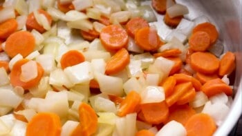 close up on sliced carrots and onions in a skillet
