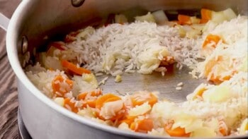 carrots, onions, and rice mixed together in a skillet
