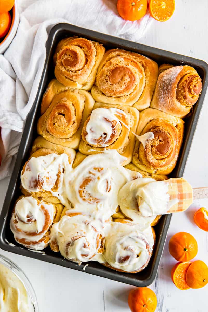 using a spatula to frost orange rolls