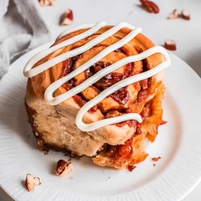 pecan caramel roll on a plate drizzled with icing
