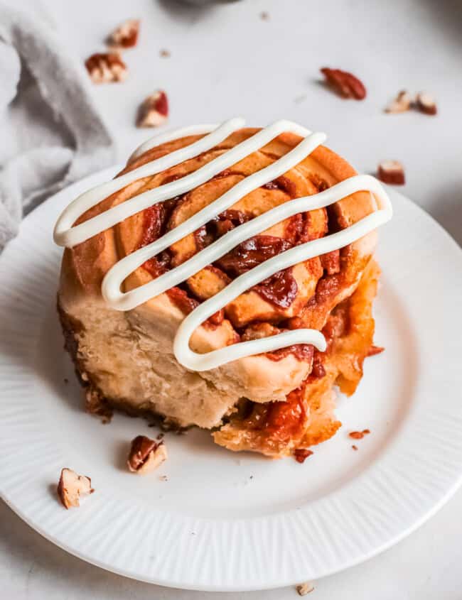 pecan caramel roll on a plate drizzled with icing