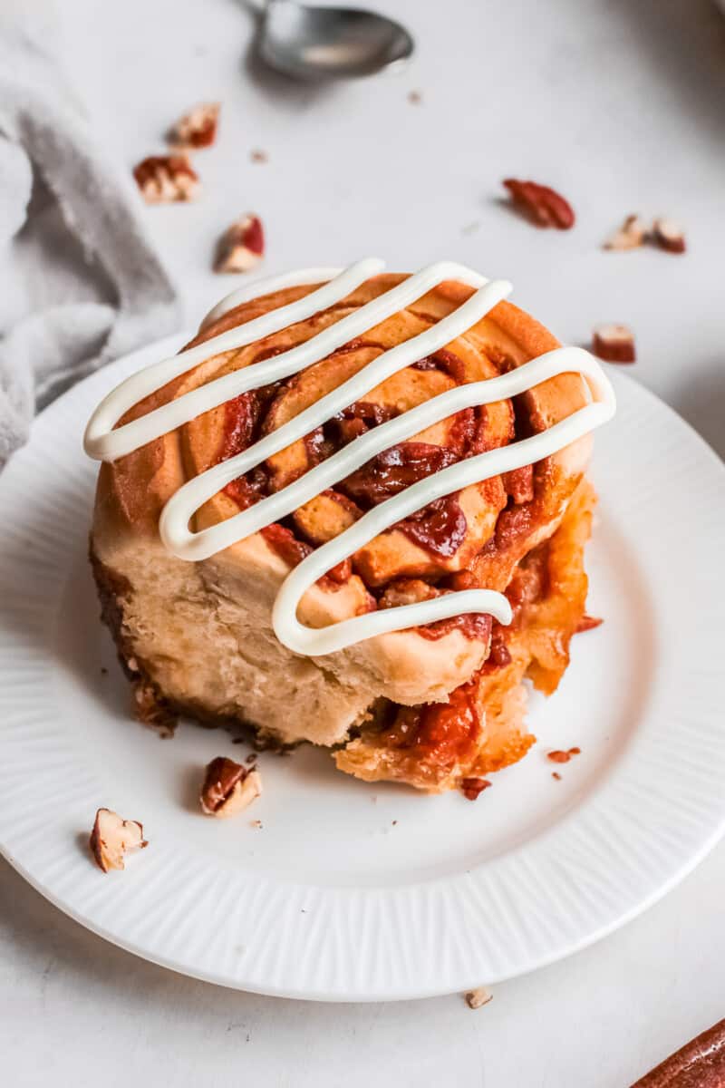 pecan caramel roll on a plate drizzled with icing