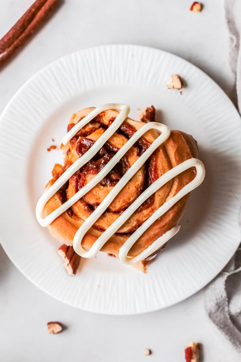 overhead pecan caramel roll on a plate drizzled with icing