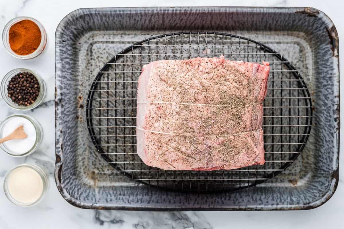 prime rib covered with seasonings on a baking pan