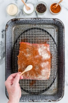 hand sprinkling spices on top of prime rib roast