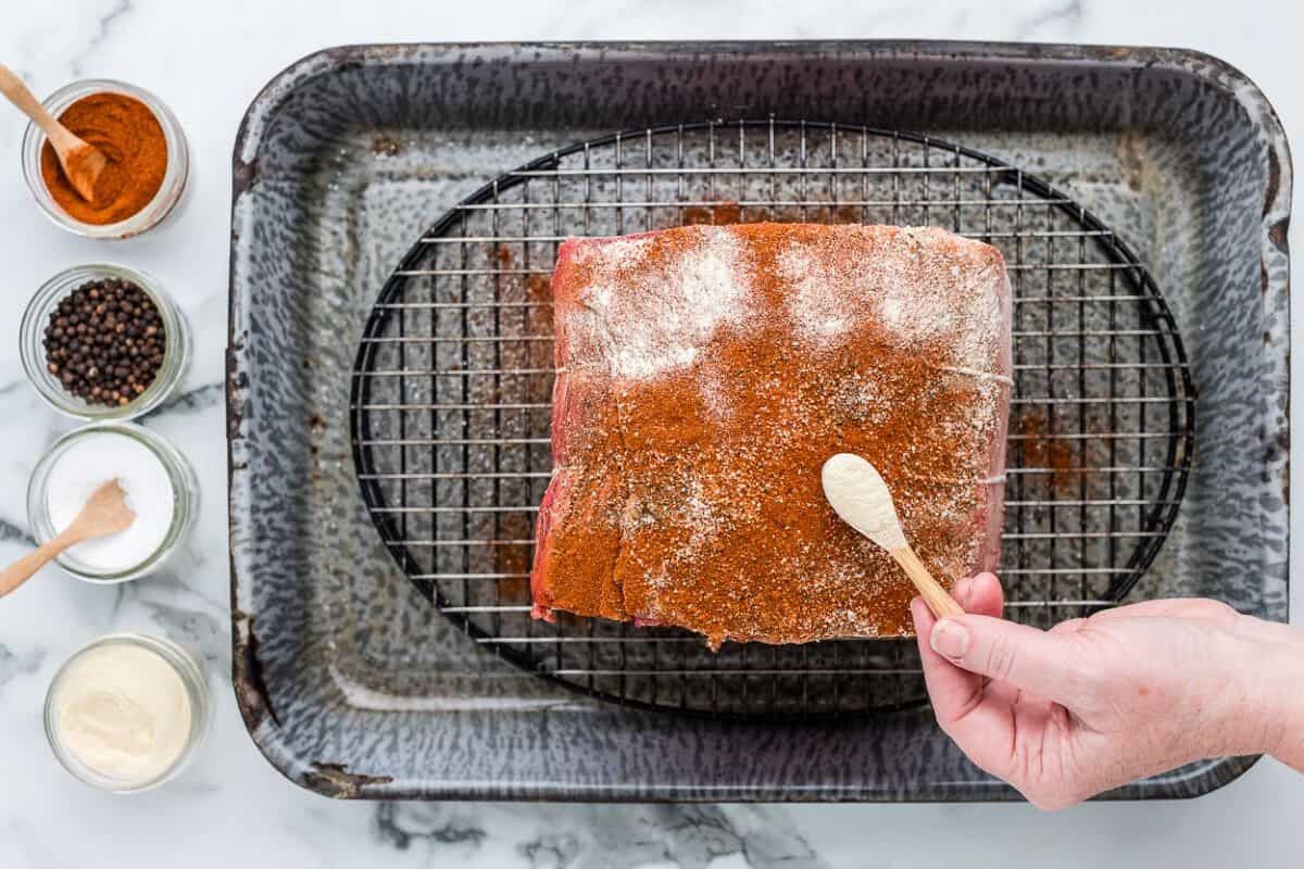 hand sprinkling spices on top of prime rib roast