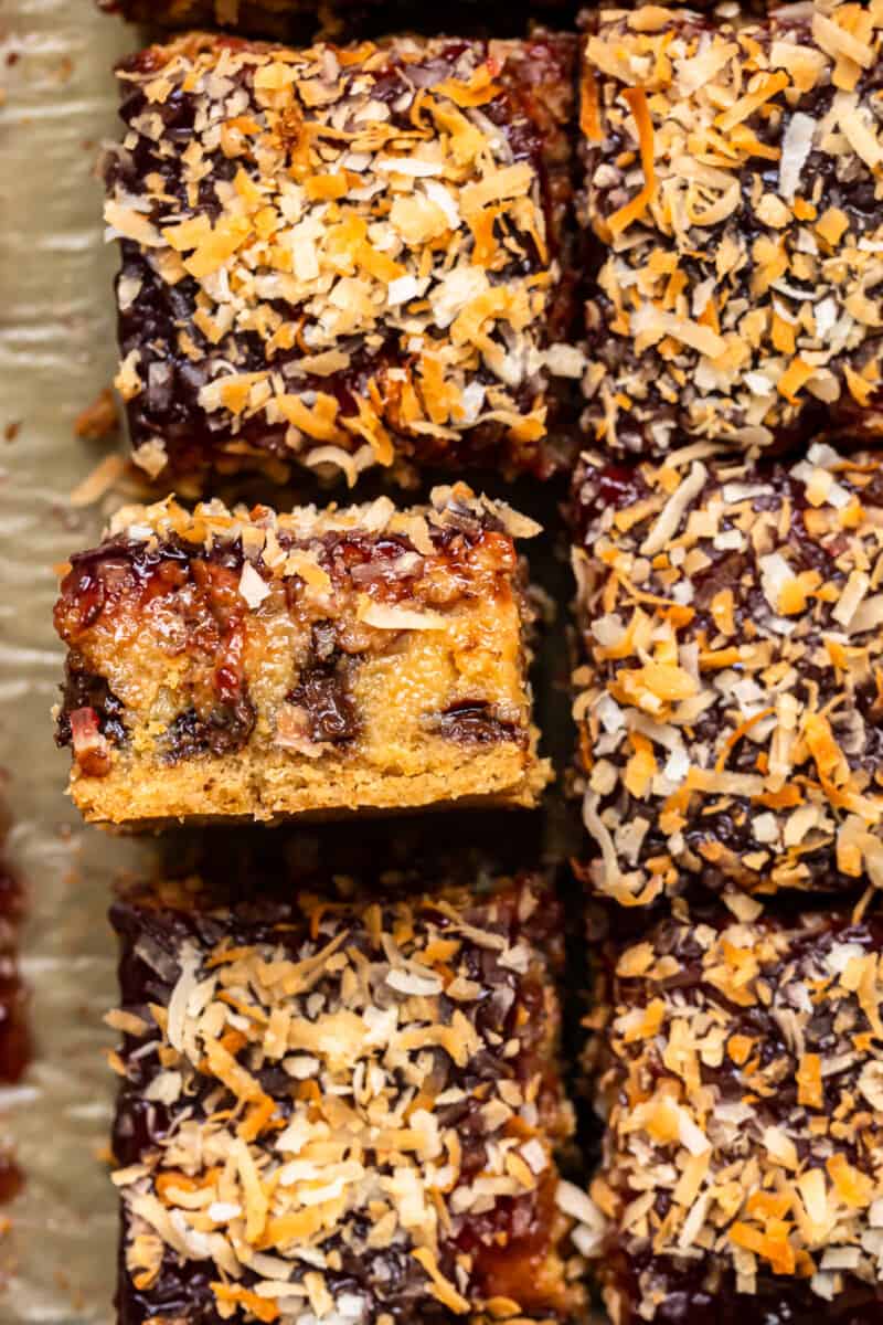 close up image of raspberry chocolate coconut bars on parchment paper