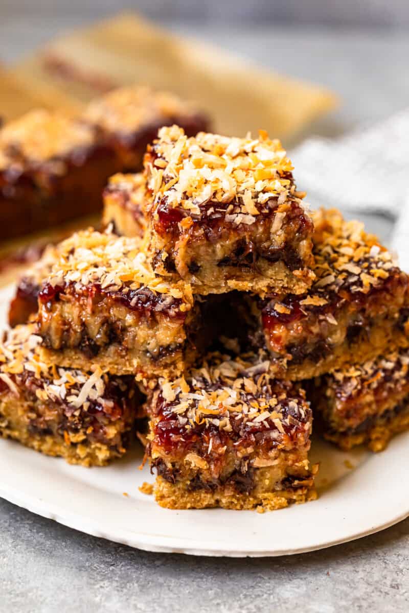 stack of raspberry chocolate coconut bars on a white serving plate