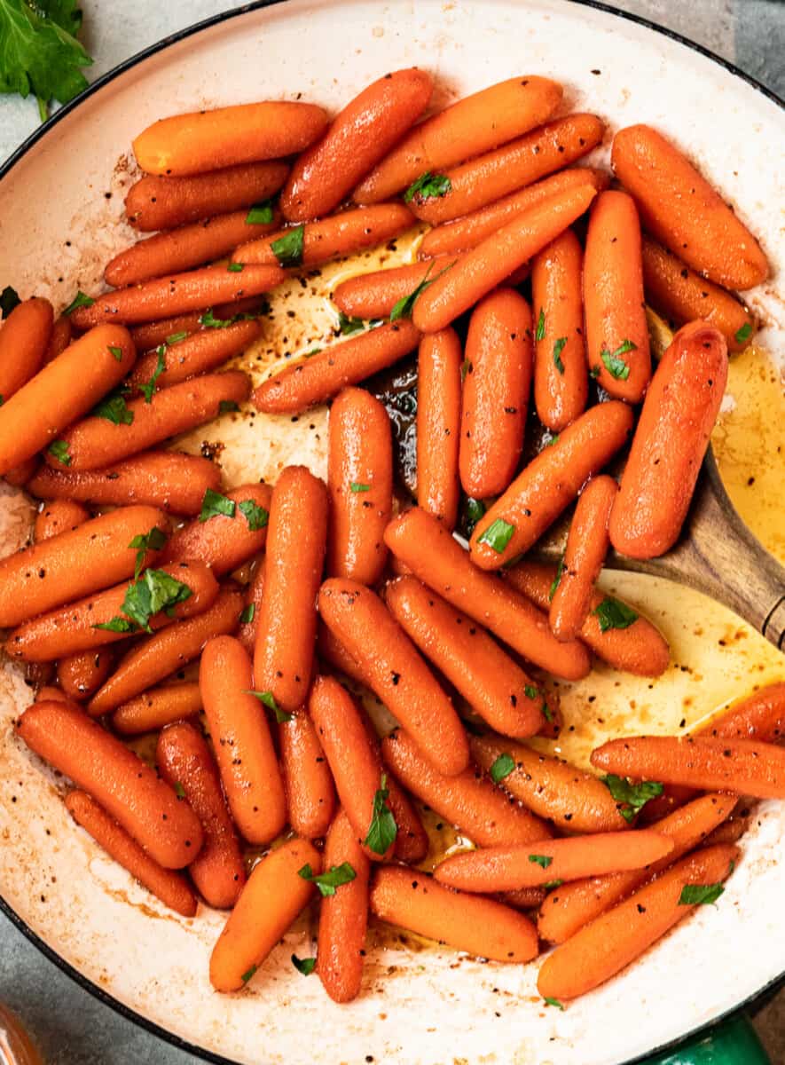 carrots in a skillet with a wood spoon