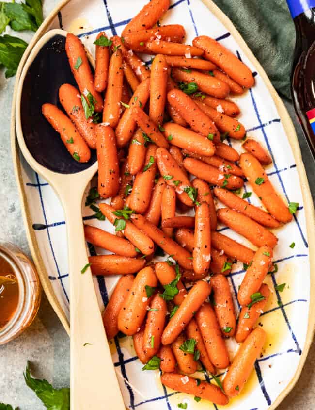 red wine glazed carrots in a serving dish with a serving spoon