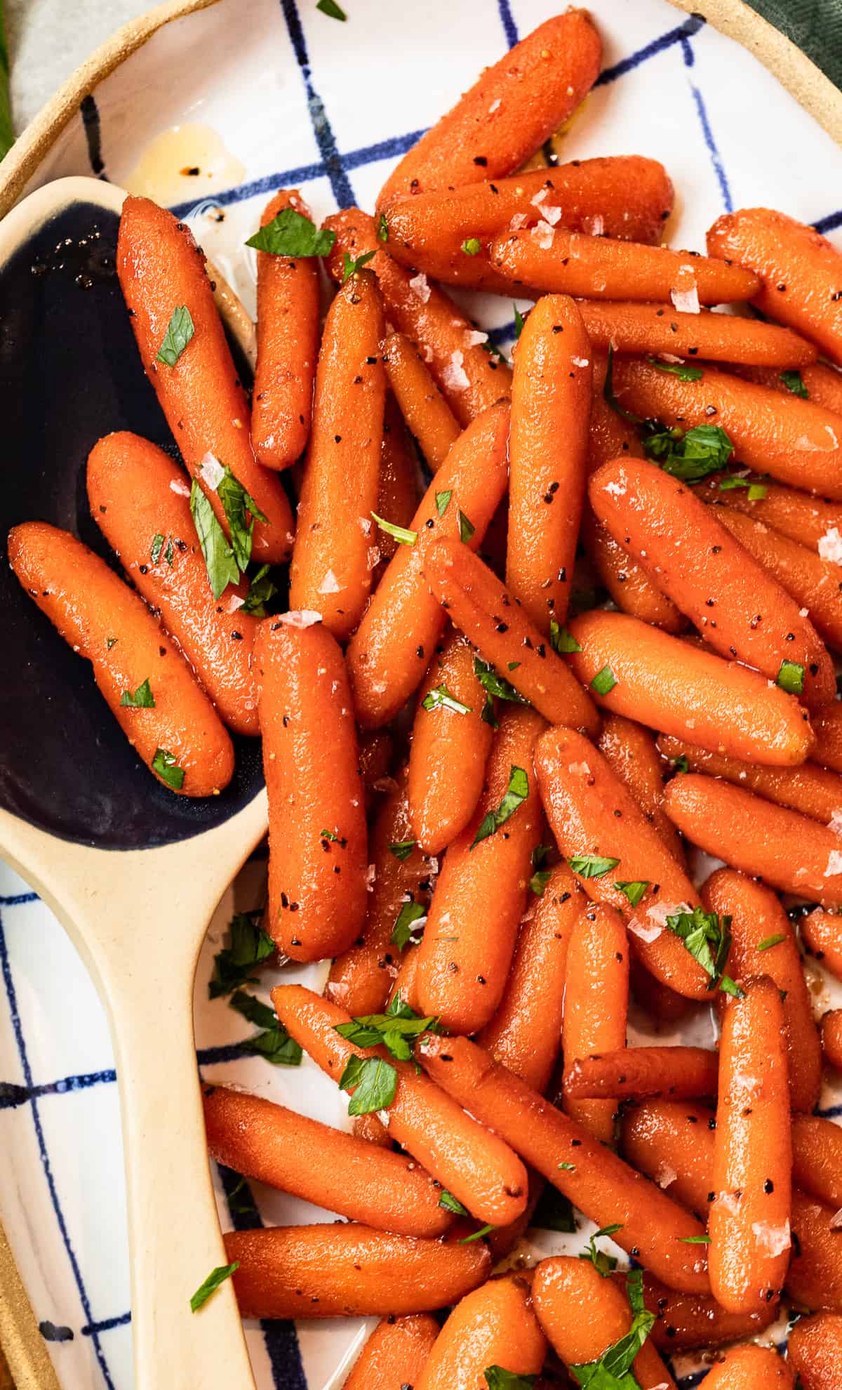 close up image of red wine glazed carrots in a serving dish with a serving spoon