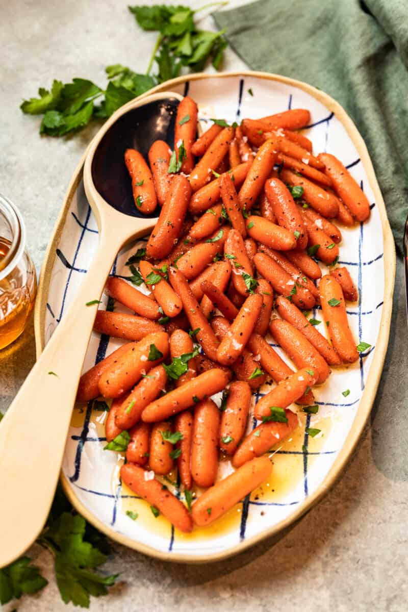 red wine glazed carrots in a serving dish with a serving spoon