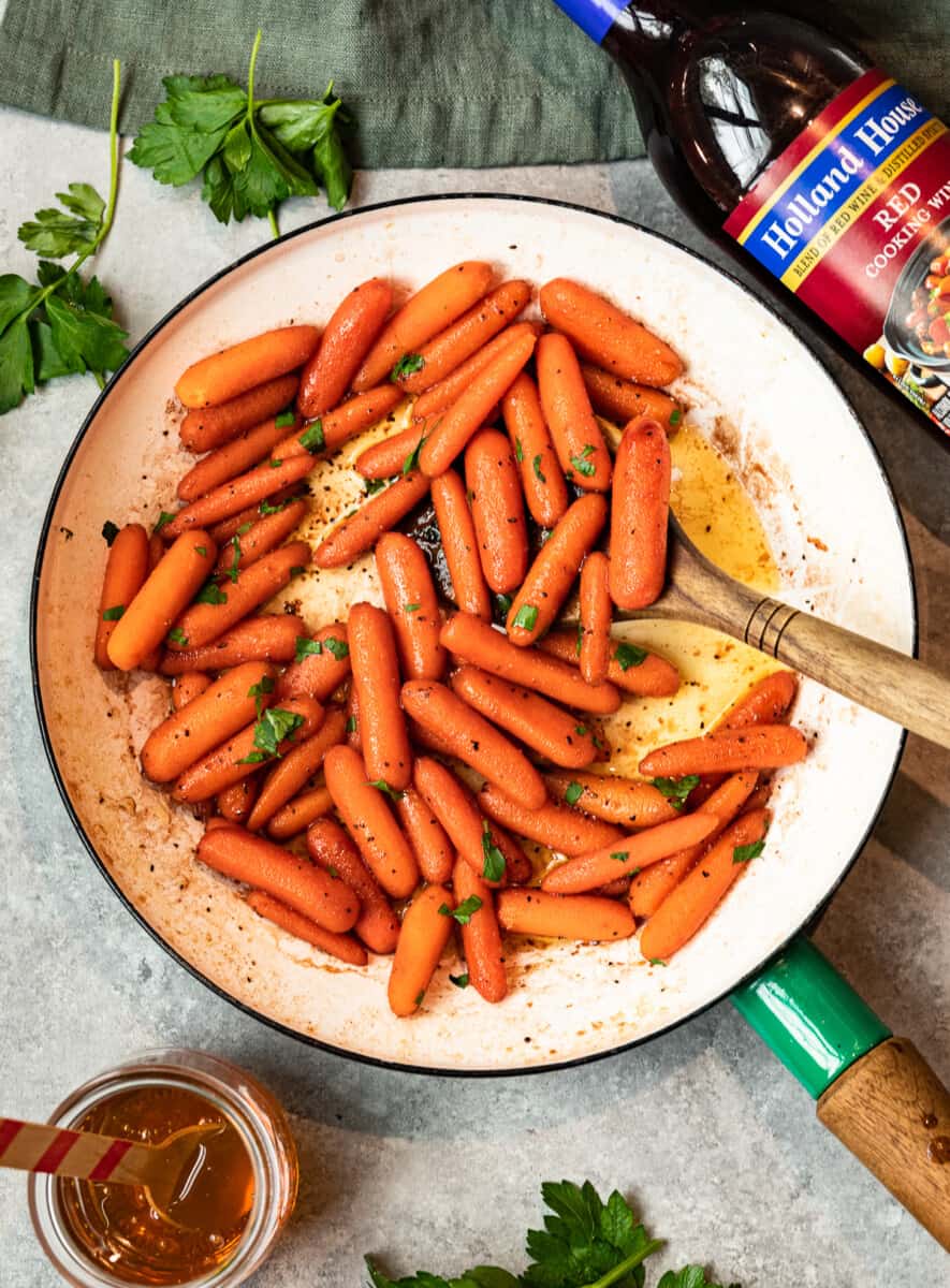 carrots in a skillet with a wood spoon