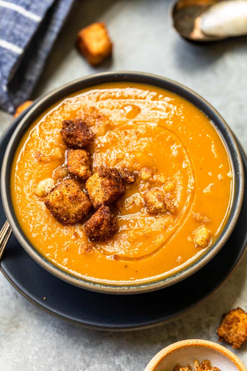 roasted butternut squash soup topped with cinnamon croutons in a black bowl